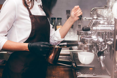 Midsection of barista preparing coffee at cafe