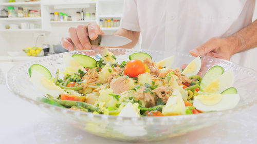 Midsection of senior man preparing food in bowl on table