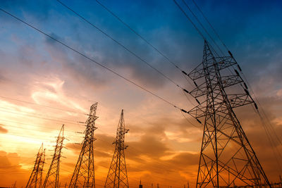 Low angle view of silhouette electricity pylon against romantic sky