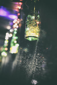 Close-up of illuminated bottle hanging at night