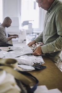 Male fashion designer packing fabric while working at workshop