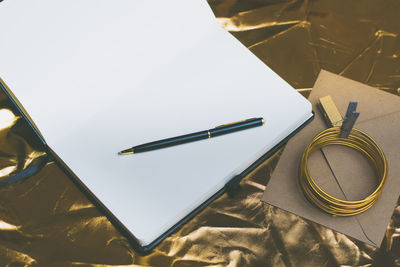 High angle view of blank book with pen on table