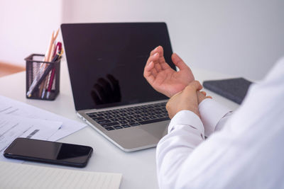 Midsection of man using laptop on table
