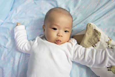 Portrait of cute baby lying on bed