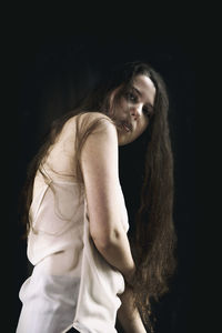 Portrait of woman standing against black background