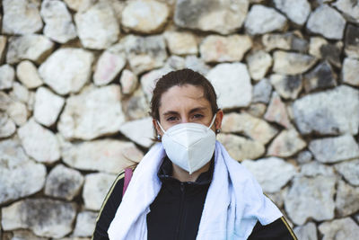 Portrait of woman standing against stone wall