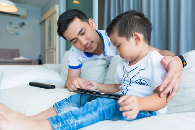 Father and son using digital tablet at home