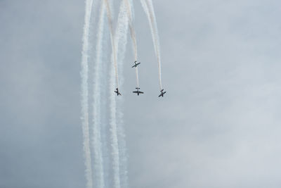 Low angle view of airplanes flying against sky during air show