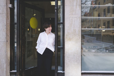 Smiling young female designer standing at doorway of studio