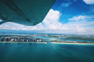 Aerial view of city by sea against sky