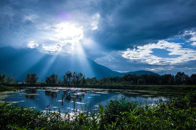 Sunbeams streaming from cloudy sky over lake