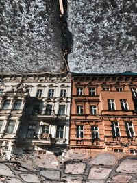 Reflection of building in water puddle on footpath