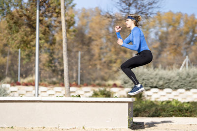 Full length of woman jumping against trees