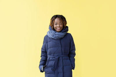 Portrait of smiling woman standing against yellow background