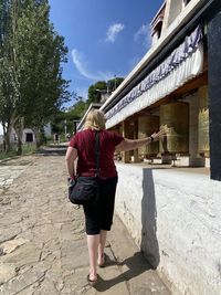 Rear view of woman walking on footpath amidst buildings