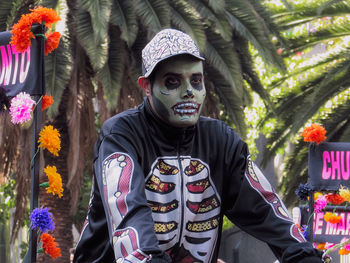 Portrait of young man standing by flowering plants