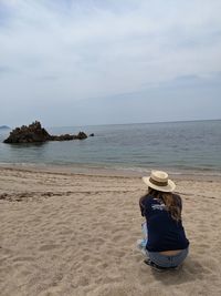 Rear view of person on beach against sky