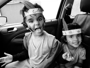 Portrait of siblings with face paint sitting in car