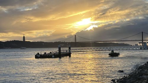 Silhouette bridge over sea against sky during sunset