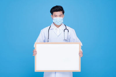 Portrait of young man standing against blue background