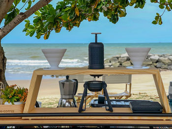 Chairs and table at beach against sky