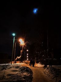 People walking on illuminated street at night