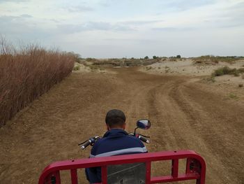 Rear view of man riding motorcycle on road