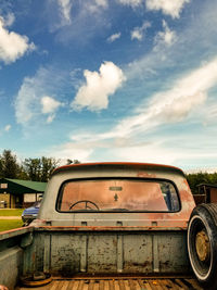 Abandoned car on field against sky