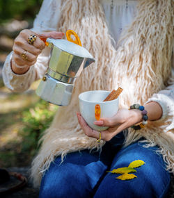 Midsection of woman holding coffee pot and cup