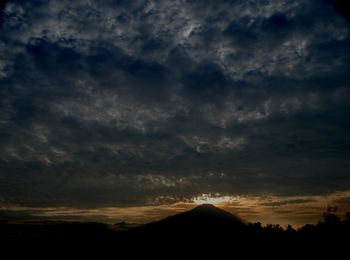 Silhouette of landscape against cloudy sky