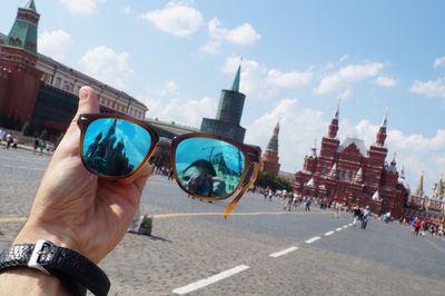 Cropped image of man holding sunglasses against red square