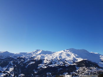 Scenic view of snowcapped mountains against clear blue sky