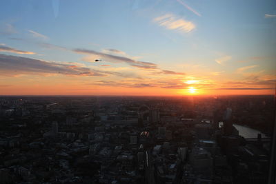 Aerial view of buildings in city against sky during sunset