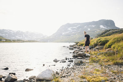 Woman standing at lake in mountains