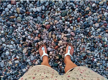 Low section of woman walking on pebbles