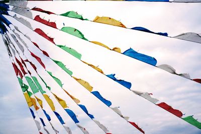 Low angle view of multi colored flags hanging against sky