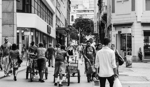 Rear view of people walking on street in city