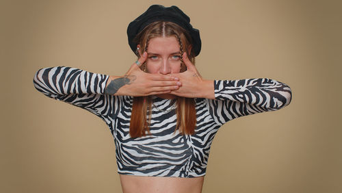 Portrait of young woman standing against wall