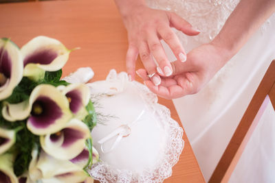 Midsection of bride removing ring on pillow