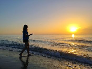 Girl  on beach against sky during sunset