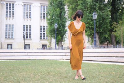 Young woman walking on lawn against building