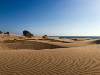 Sand dunes in desert against clear blue sky