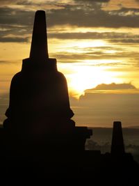 Silhouette built structure by sea against sky during sunset