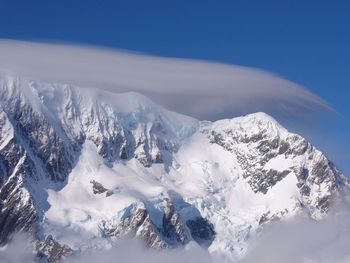 Scenic view of snowcapped mountains against blue sky