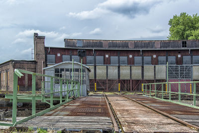 Abandoned railroad tracks amidst buildings against sky