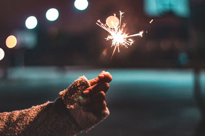 Person holding sparkler at night