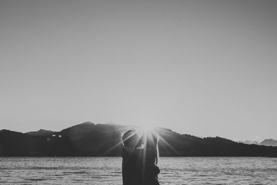 Side view of couple kissing by lake against clear sky