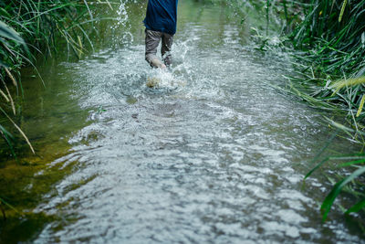 Low section of man standing in water stream