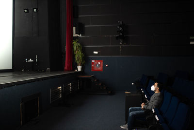 Man wearing mask sitting in theater