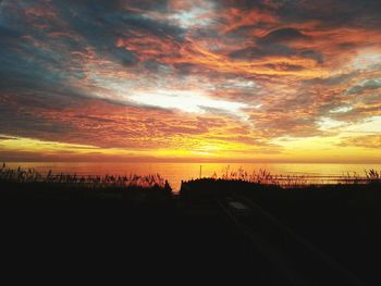 Scenic view of sea against cloudy sky at sunset
